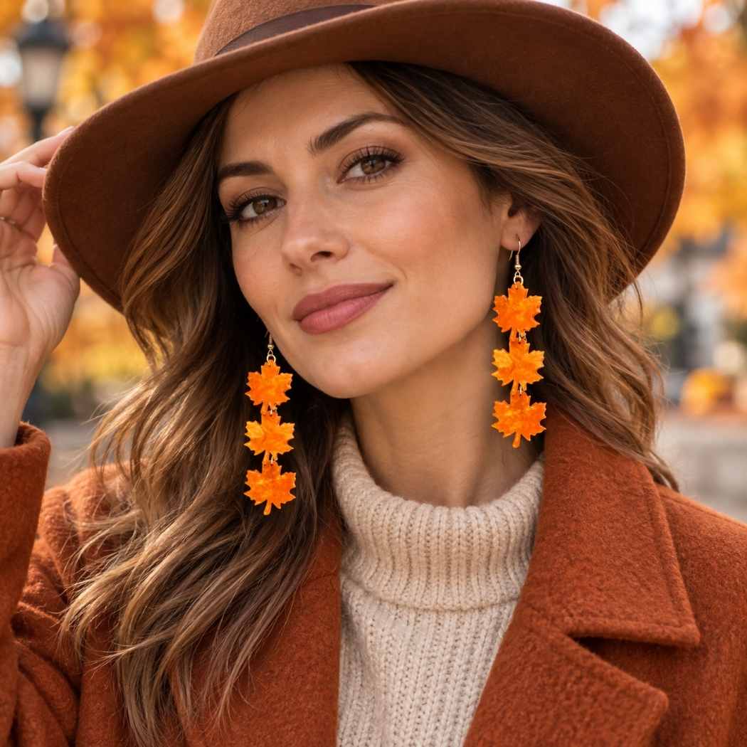 Orange maple leaf dangle earrings in acrylic with triple leaf drop design on model
