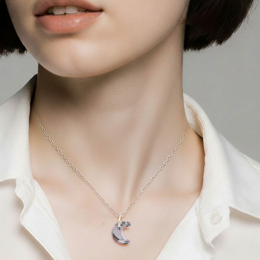 Necklace with a moon pendant worn by a person in a white shirt against a neutral background