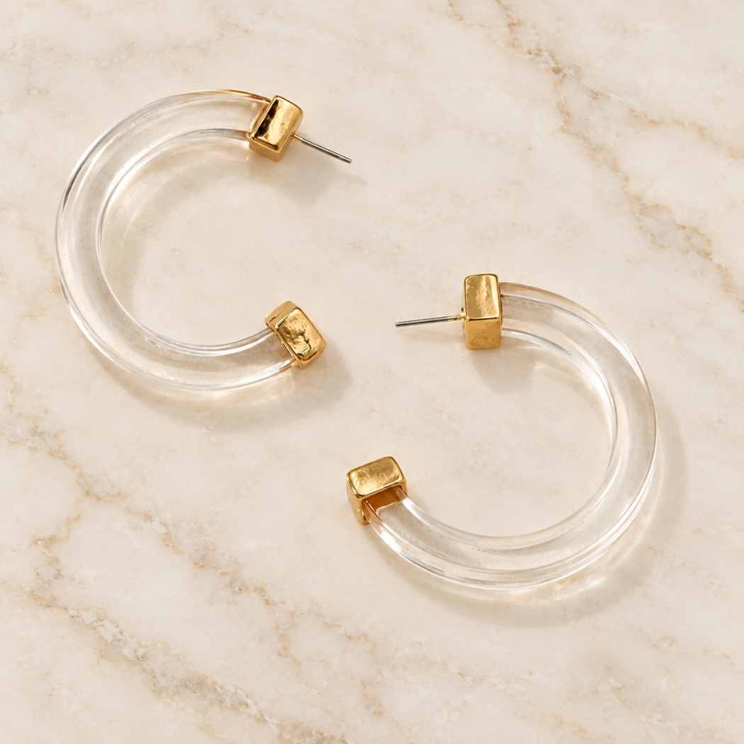 Clear acrylic hoop earrings displayed on marble surface