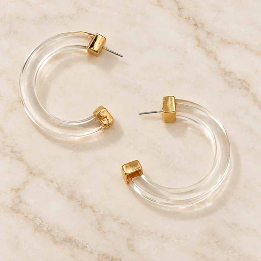 Clear acrylic hoop earrings displayed on marble surface