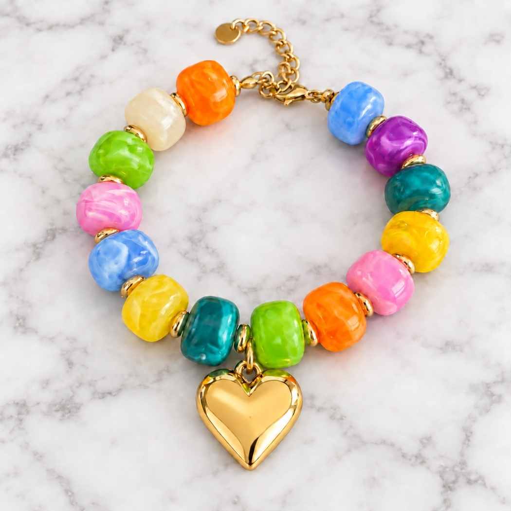Multicolour acrylic bead bracelet with gold heart charm on a marble surface