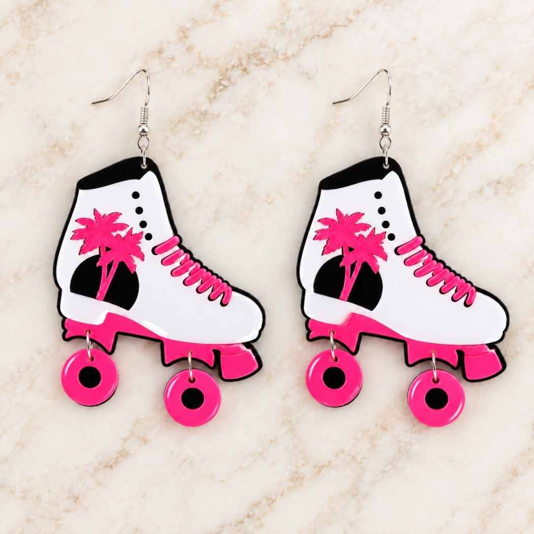 Pink roller skate earrings displayed on marble surface