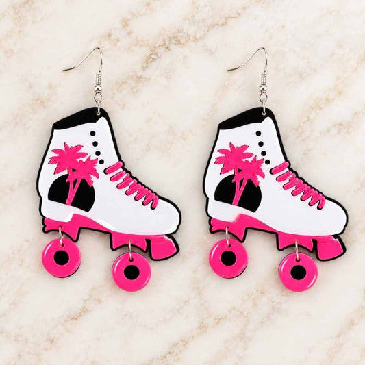 Pink roller skate earrings displayed on marble surface