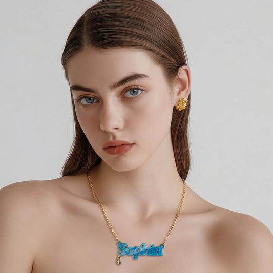 Woman wearing a gold necklace and earrings on a plain background