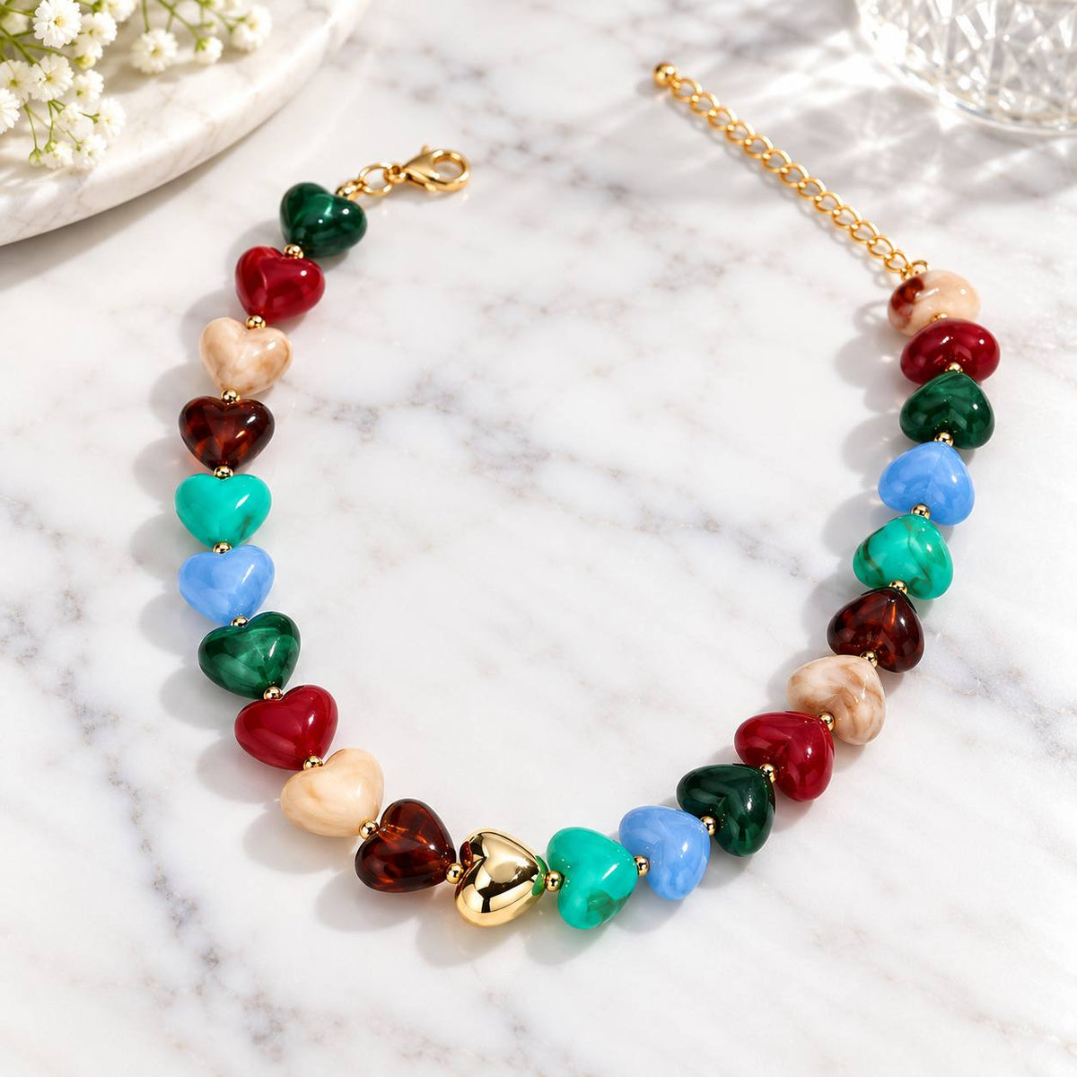 Colourful chunky heart bead necklace with gold-tone accents on white marble