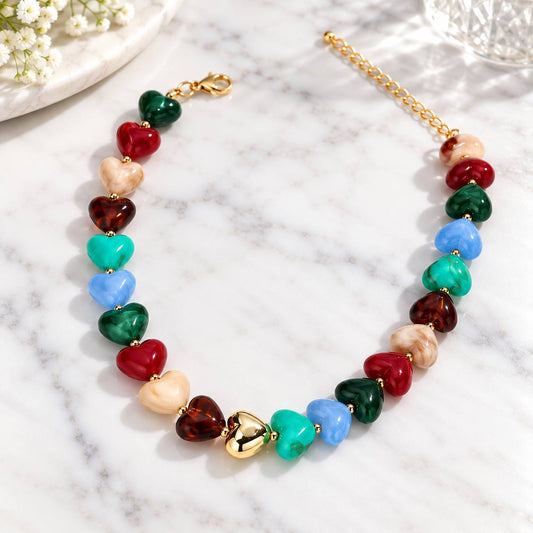 Colourful chunky heart bead necklace with gold-tone accents on white marble